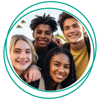 A group of four smiling young people posing together outdoors.